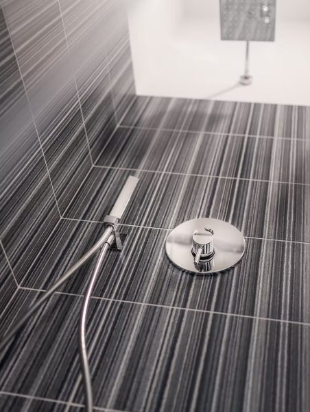 Doccia moderna con piastrelle grigie e rubinetteria cromata.