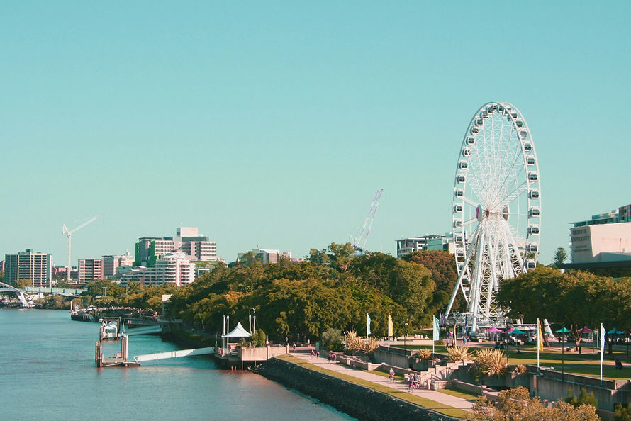 A photograph of Southbank in Brisbane featuring 'the eye' ferris wheel and the Brisbane river.
