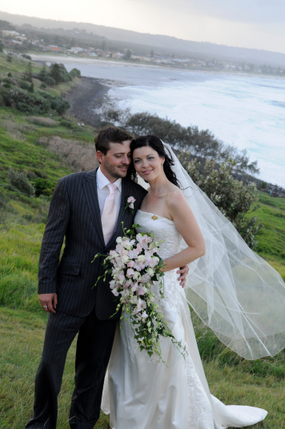Bride and Groom posing for photo in front of ocean backdrop - Mel Rose Bride