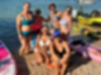 Friends posing on beach with pontoon and paddleboards