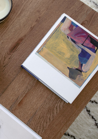 Close-up of abstract art book on wood coffee table with neutral decor styling.