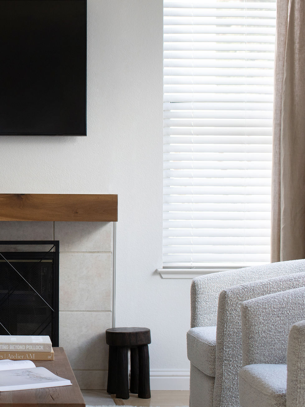 Modern neutral living room with textured rug, wood mantel fireplace, and comfortable seating