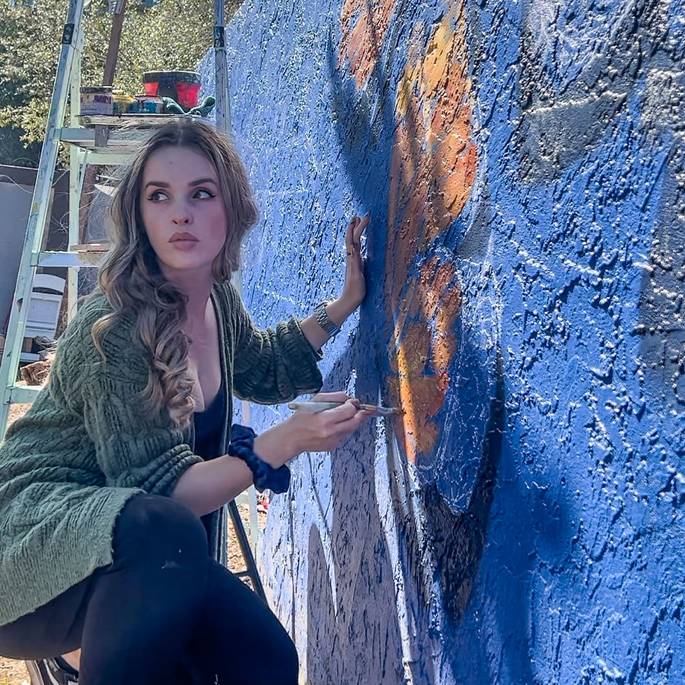 Claudia Mattias painting monarch butterfly mural on residential backyard wall in Tampa FL