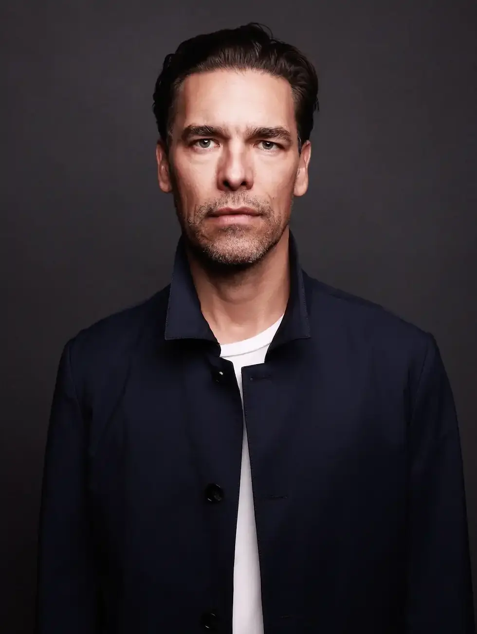 Thomas La Barbera Christensen in a white shirt, posed against a plain gray studio background.