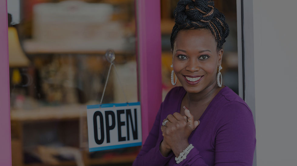 Smiling business owner outside in front of the front entrance of her business.