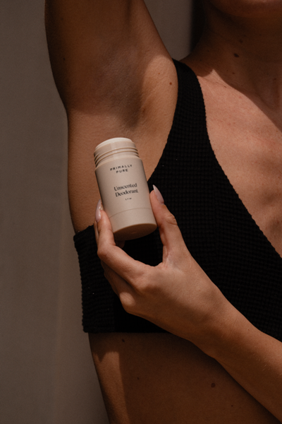 Woman applying Primally Pure deodorant to underarm, emphasizing aluminum-free, natural odor protection