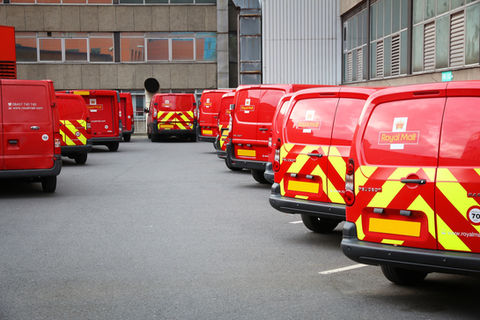 Fleet of Royal Mail vans with chevron safety markings lined up at depot