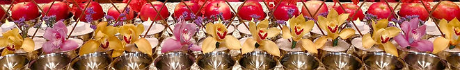 Rows of scented water, flowers, incense, light, and fruit offerings