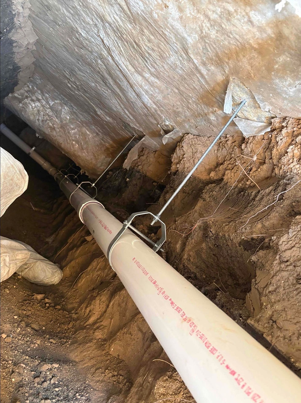 Plumbing services installing underground PVC pipes.