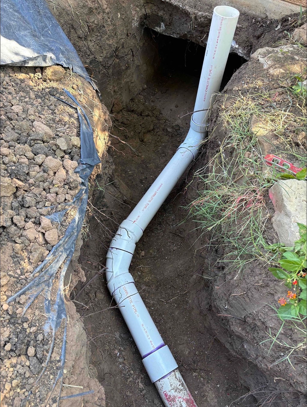 New PVC pipe installation for plumbing services in a trench.