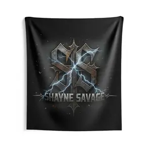 A square, black fabric wall tapestry hanging flat against a white wall. The graphic features a dark, textured, metallic 'SS' monogram with a sharp vertical cross in the center, struck by electric blue lightning. The text 'Shayne Savage' is written below in heavy metallic lettering, with faint orange sparks floating in the dark background.