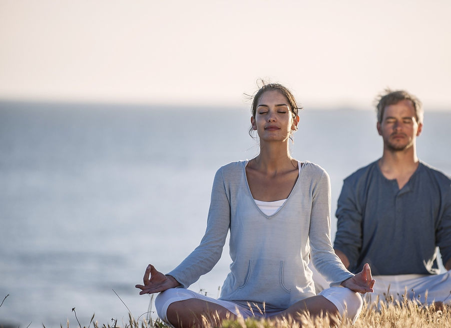 Pareja meditando junto al mar