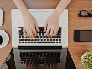 Hands typing on a computer at a very clean desk