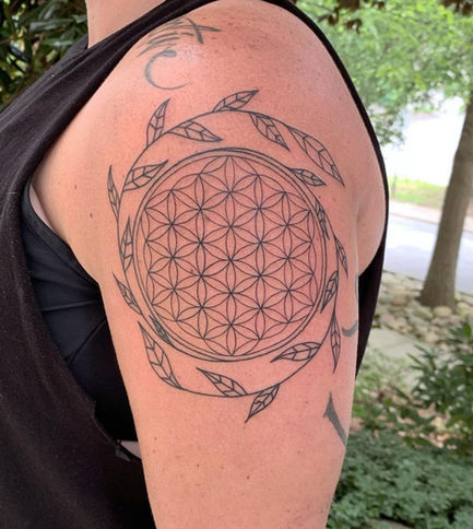 Circular geometric tattoo with botanical leaves circling the design.