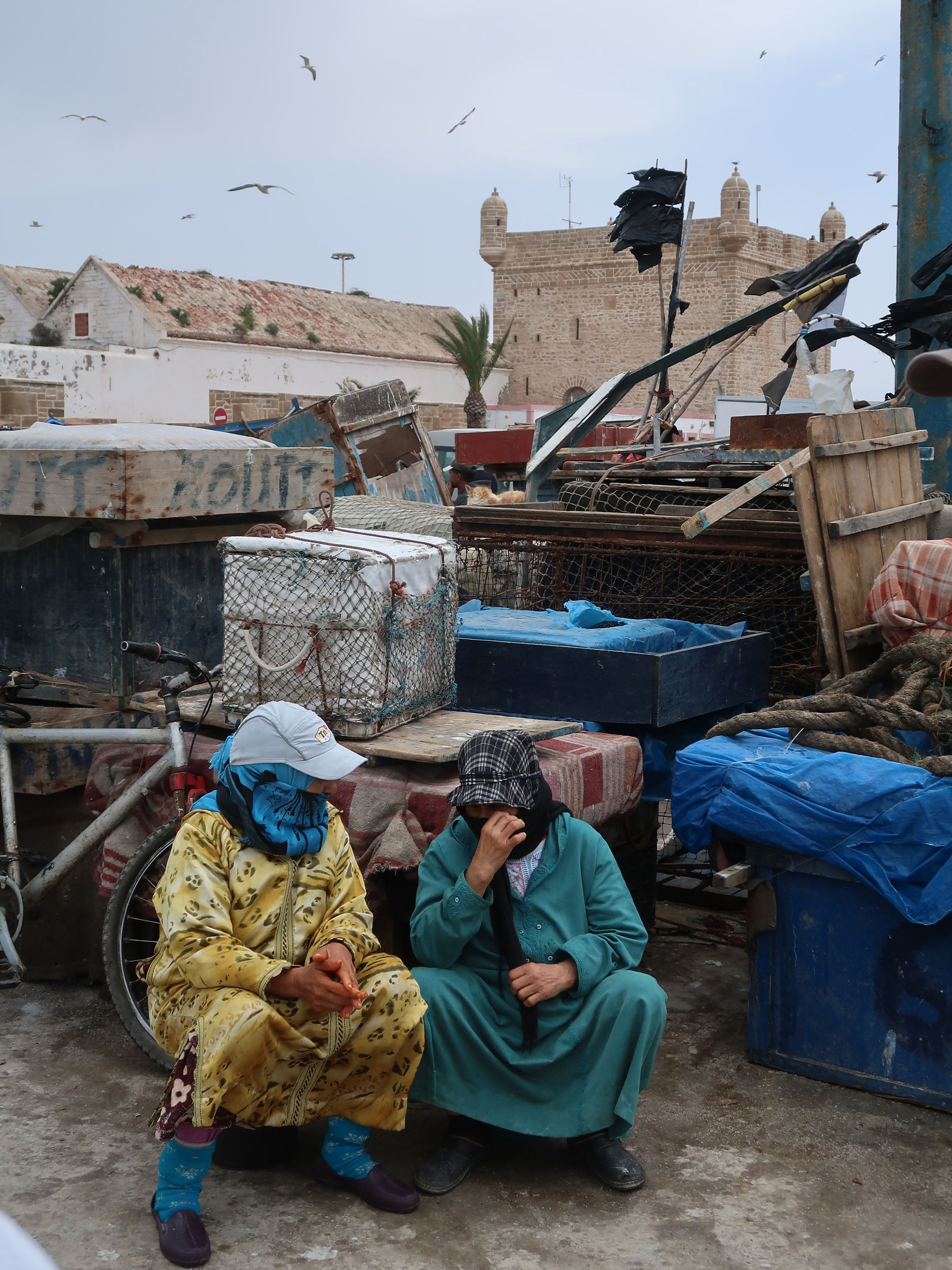 Mulheres sentadas à conversa no porto de Essaouira, Marrocos