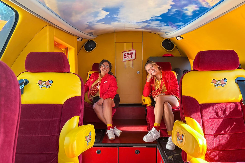 Two smiling women in red jackets sit inside a colorful vehicle with yellow and red seats. Oscar Mayer logo visible in the background.
Hot Diggity Dog! The Oscar Mayer Wienermobile is coming to Orlando and you could be driving it!