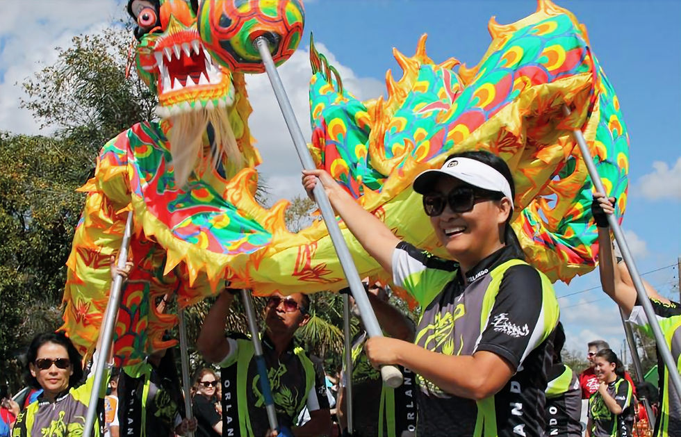 Parade scene with smiling people in green jerseys performing a dragon dance. Bright, colorful dragon costume against a sunny outdoor backdrop. Central Florida Dragon Parade Lunar New Year