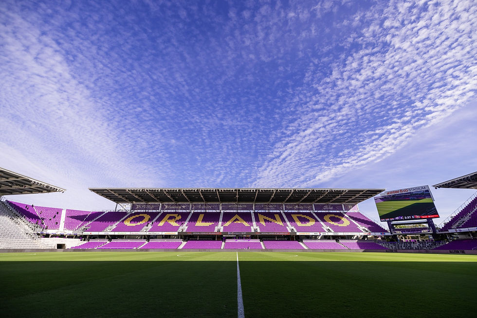 Empty stadium with purple and yellow seats under clear blue sky. Banners read "Walt Disney World." Calm mood. Orlando City SC