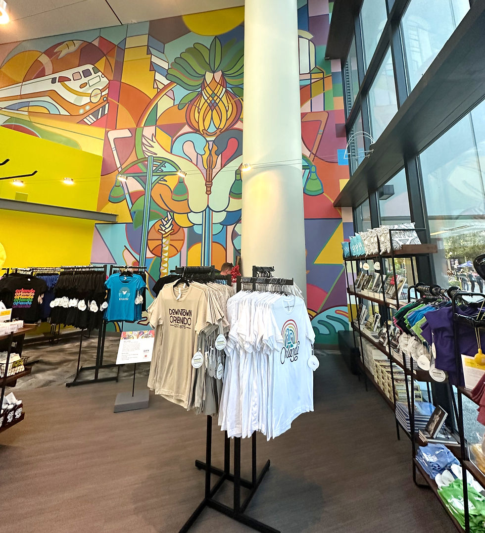 Downtown Orlando. Discover DTO. Colorful store interior with vibrant mural, racks of T-shirts with "Orlando" prints, and large windows. Energetic, modern atmosphere.