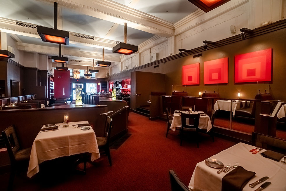 Empty, elegant restaurant interior with red carpeting, white tablecloths, abstract red artwork, modern lighting, and a calm atmosphere.