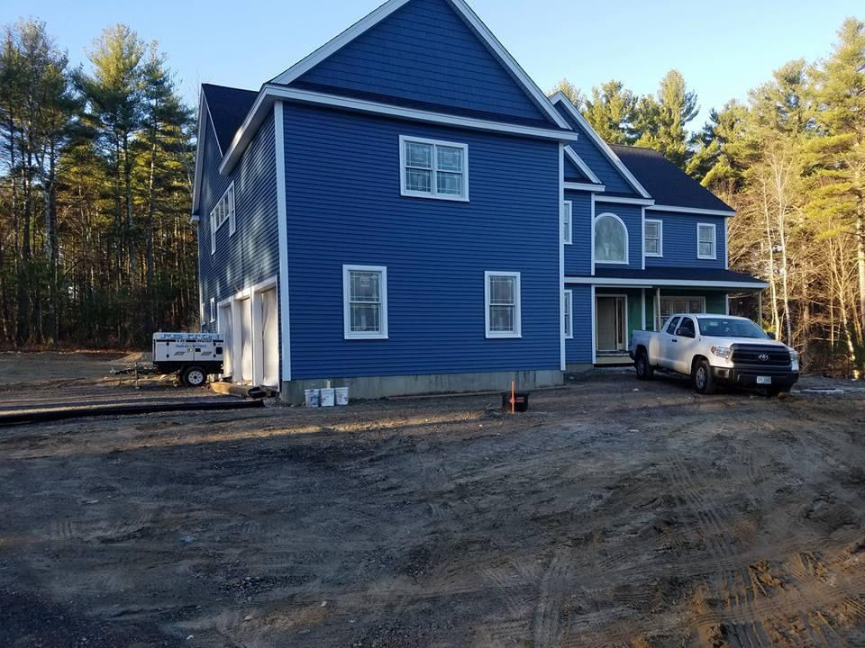 Expanded view of newly painted colonial-style home in New England, featuring a three-bay garage and blue clapboard siding, with exterior painting by T&B Paint Pros.