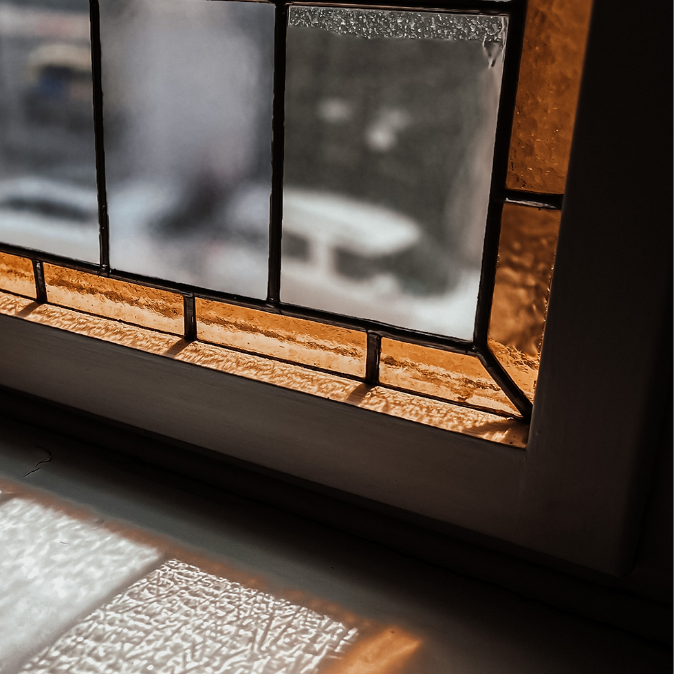 Helles Buntglasfenster mit ästhetischen Glasdetails, durch das warmes Licht fällt und eine sanfte Atmosphäre entsteht.