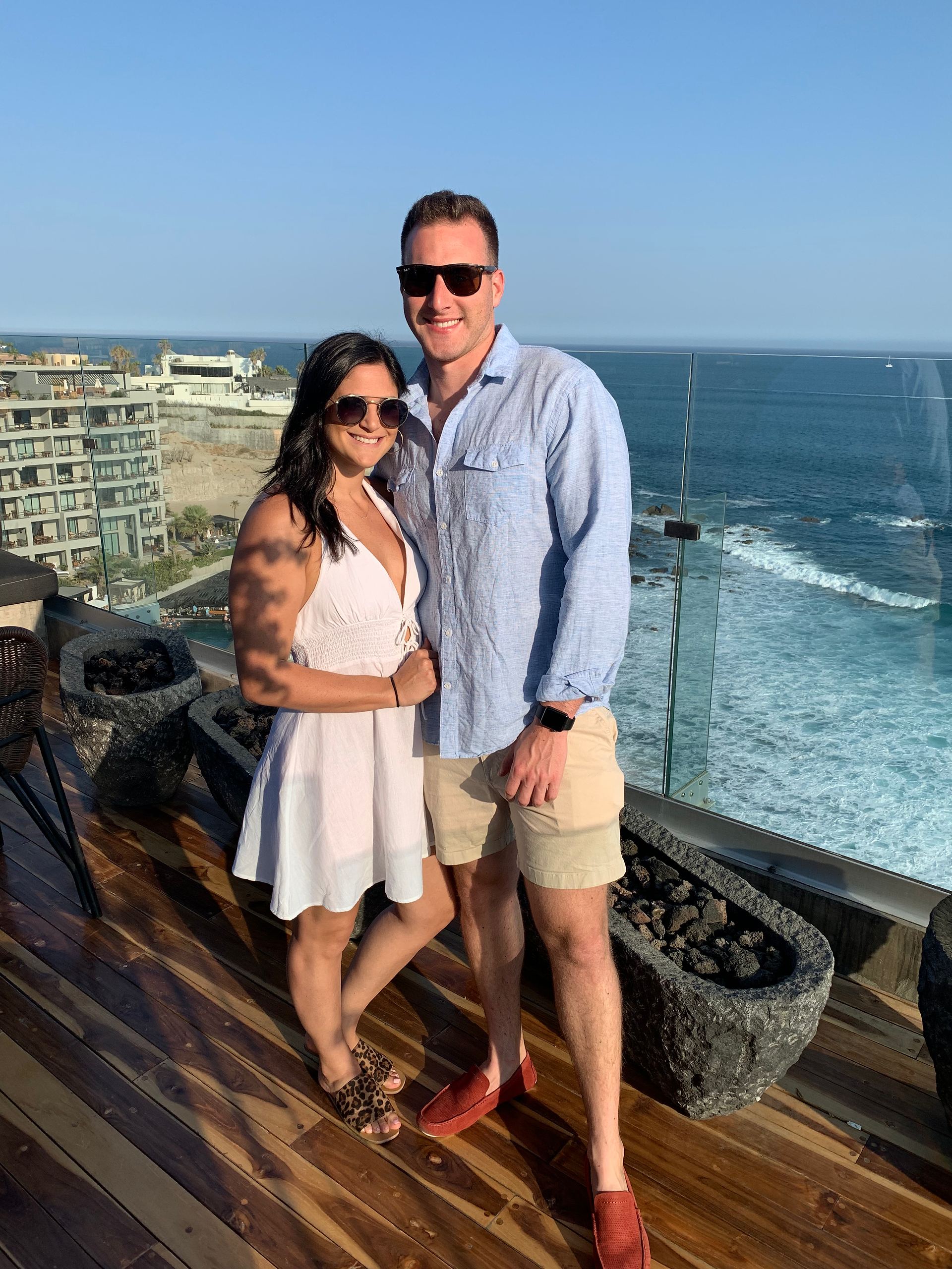 husband and wife posing for a photo at The Cape hotel balcony overlooking the beach 