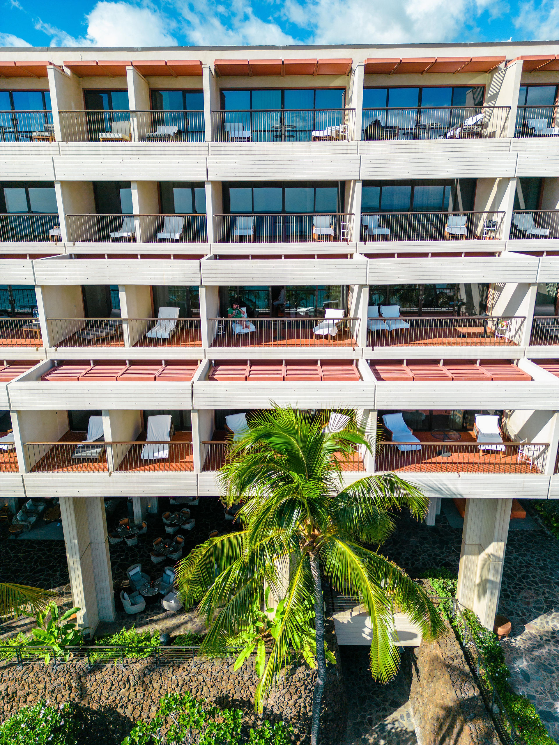 white and orange colored balconies at the Mauna Kea resort with a man sitting on a white lounge chair 