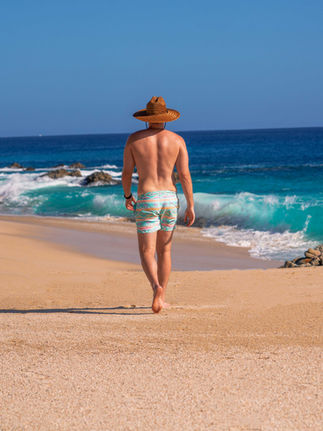 Man in sombrero and swim suit walking along the beach in Cabo San Lucas