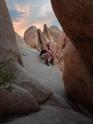 Visitor resting on smooth granite between towering rock fin