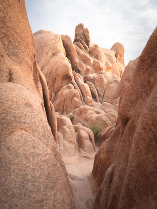 Narrow passageway opening toward sunlit rock spires.