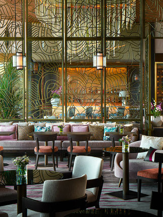 dining room filled with multiple chairs and tables with colorful shades of fabric and a large glass metal accent wall with a large chandelier hanging from the ceiling