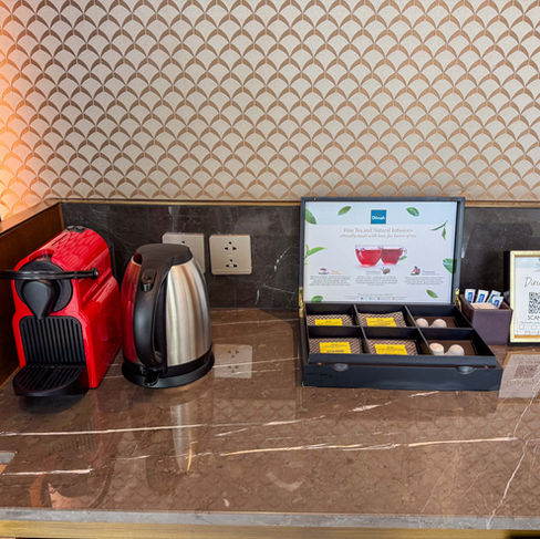 red coffee machine and a silver coffee server next to a box of espresso coffees on top of a stone counter top