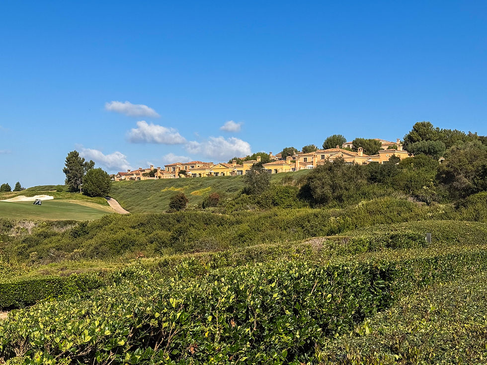 Yellow 2 story villas perched on top of a hill surrounded by landscaping and a golf course below