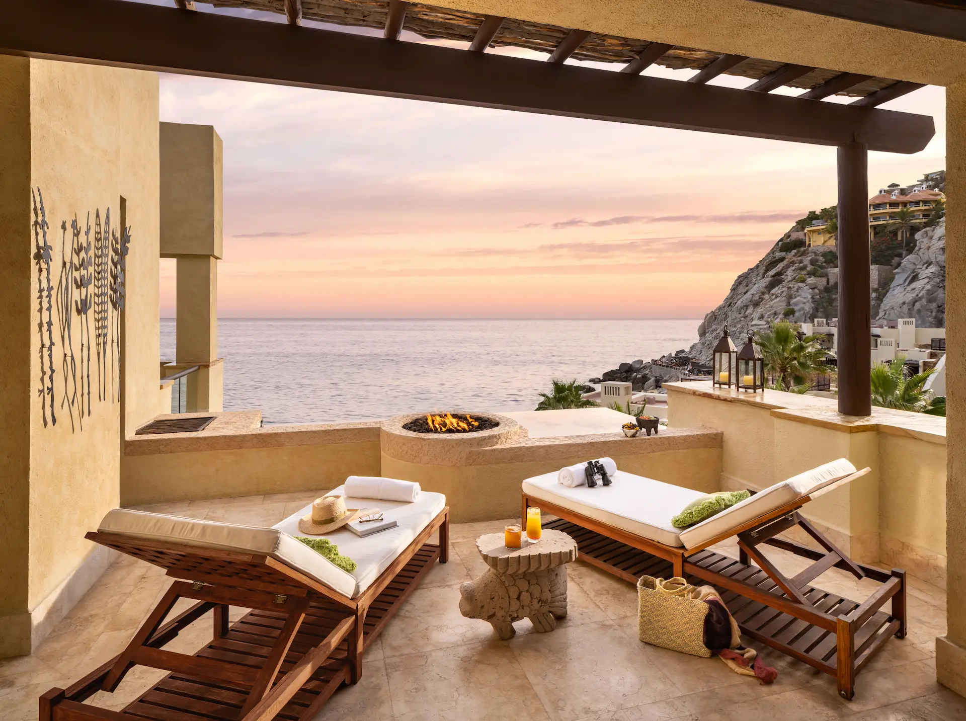 outdoor lounge chairs and patio with fireplace overlooking the mountain and beach at Cabo
