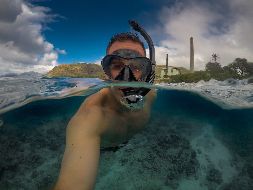 Split shot above and under water of a man snorkeling at Electric Beach on OAHU