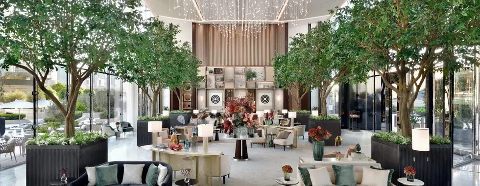 interior hotel lobby featuring large trees and elegant couch seating