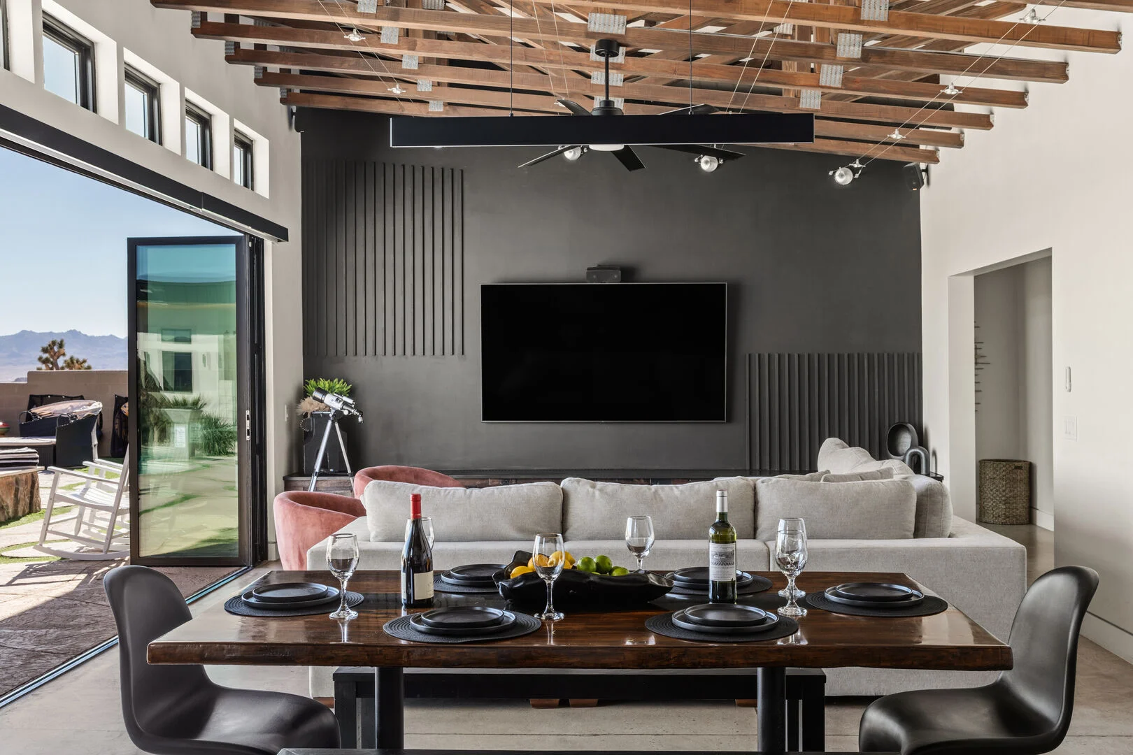 exposed wooden rafters with modern interiors, a dining room, and large couch with tv in the living room 