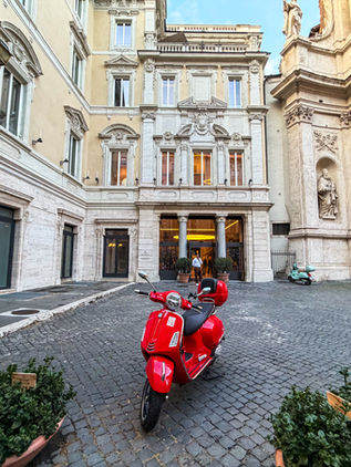 A Red Vespa Scooter parked outside of the Roman Stone facade at the Six Senses Rome property