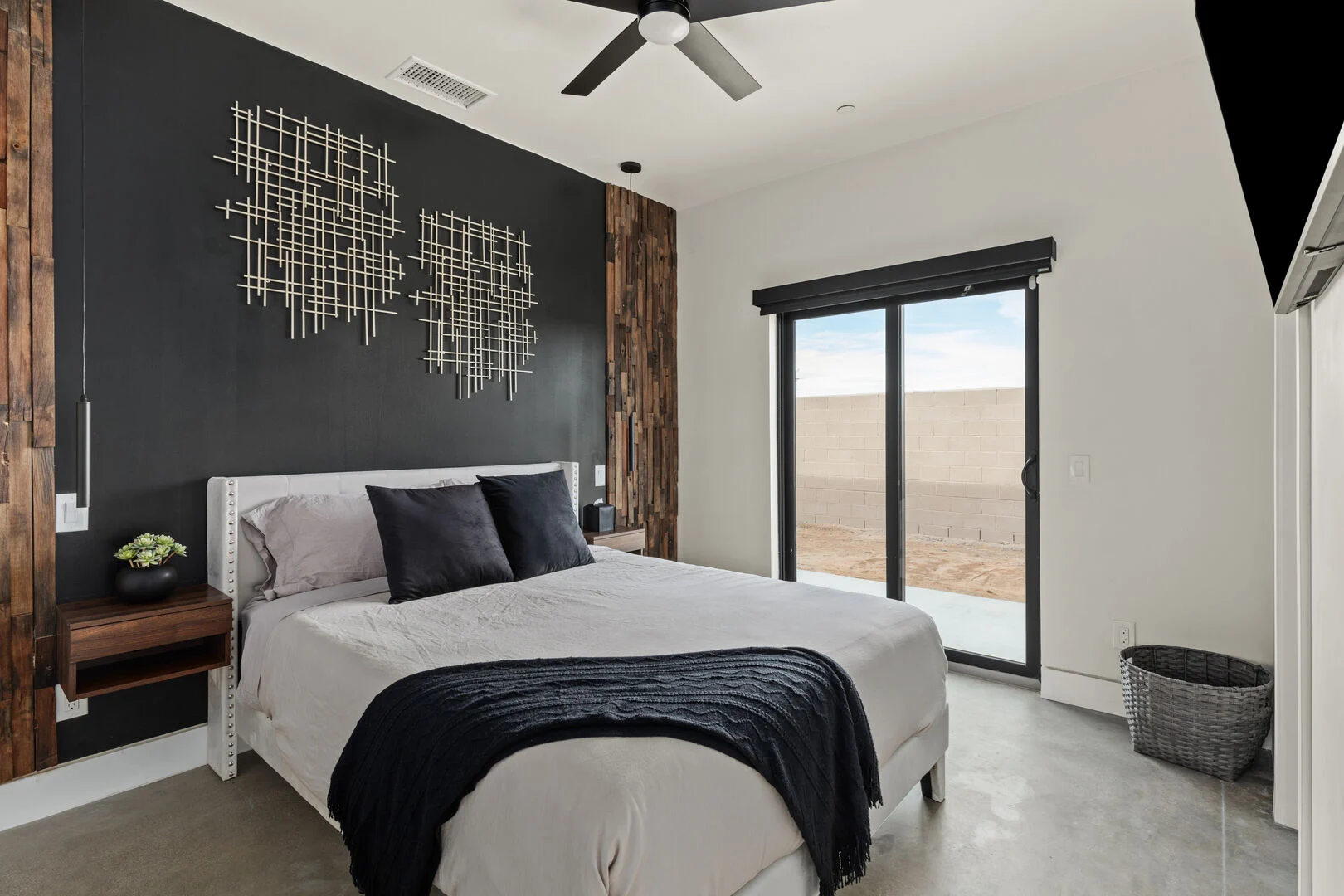 blue and brown accented guest bedroom with a kind size bed and sliding doors to the outside 