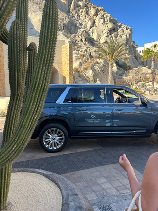 Waldorf Astoria Los Cabos Pedregal Private SUVs for airport shuttle and transportation to and from the hotel at the outdoor lobby surrounded by cactus, palm trees, and mountain rocks