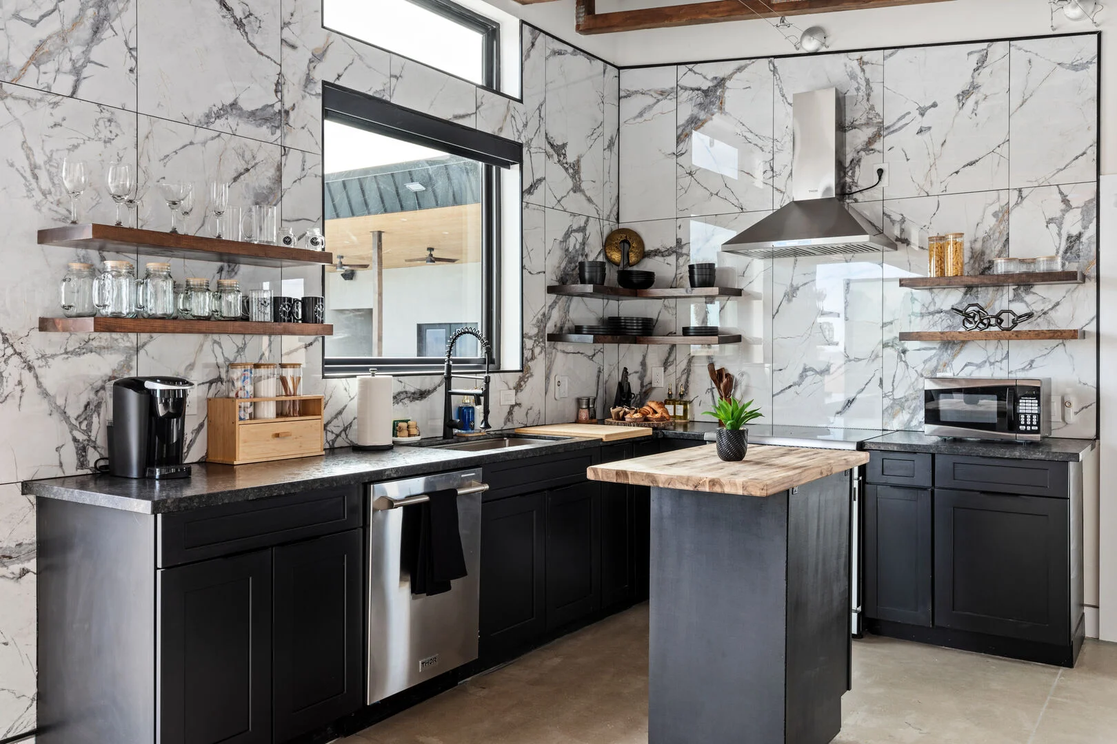 stainless steel appliances in a kitchenette with white and grey stone marble walls 