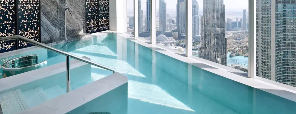 rooftop spa with beautiful hydrohtherapy pool next to large glass windows overlooking the Dubai city skyline