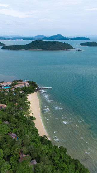 aerial view of the sandy beach surrounded by lush green vegetation and islands in the ocean distance at Sri Panwa in Phuket Thailand