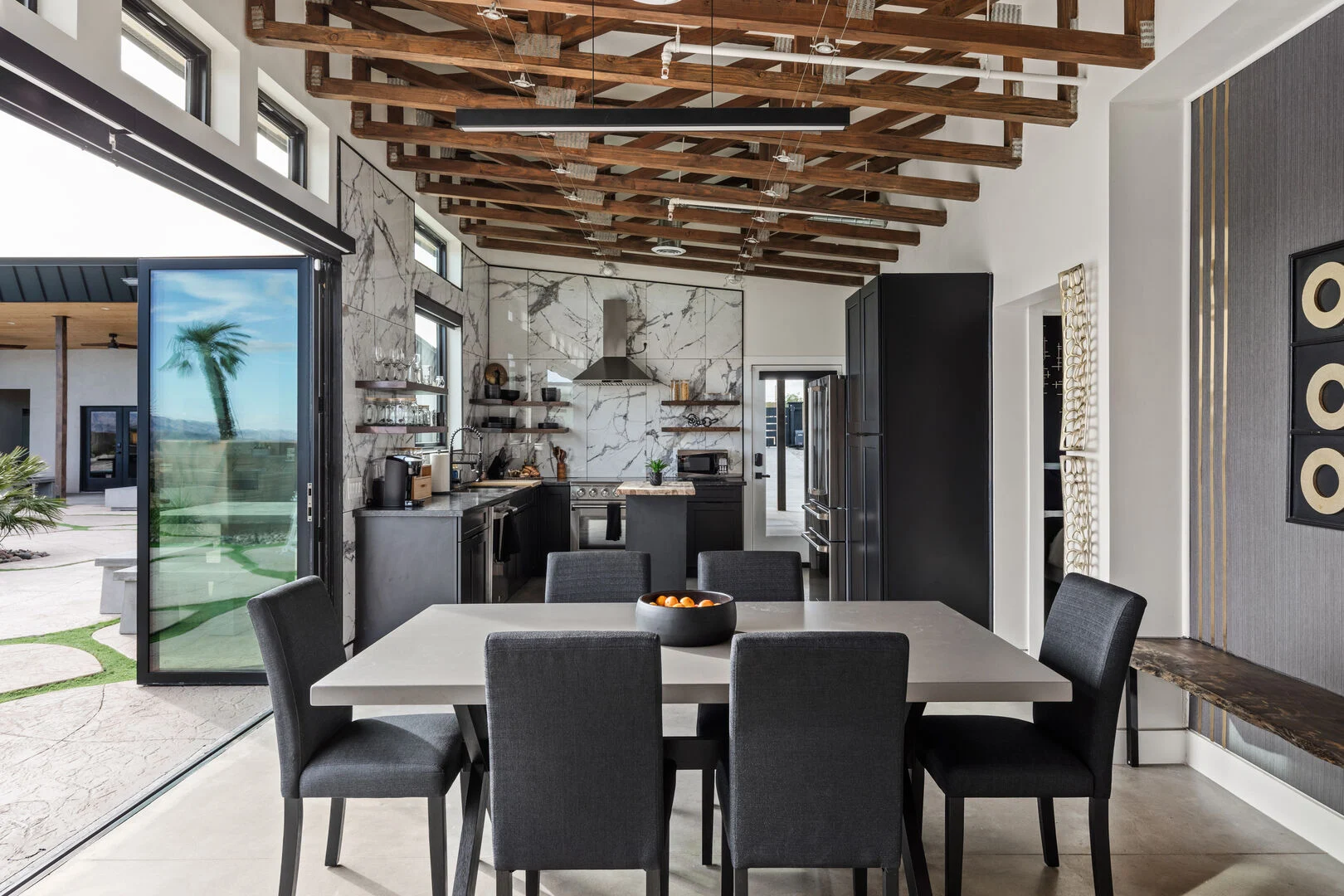 open air concept with large glass sliding doors opening to the dining room and kitchen with exposed wood beams in the ceiling 