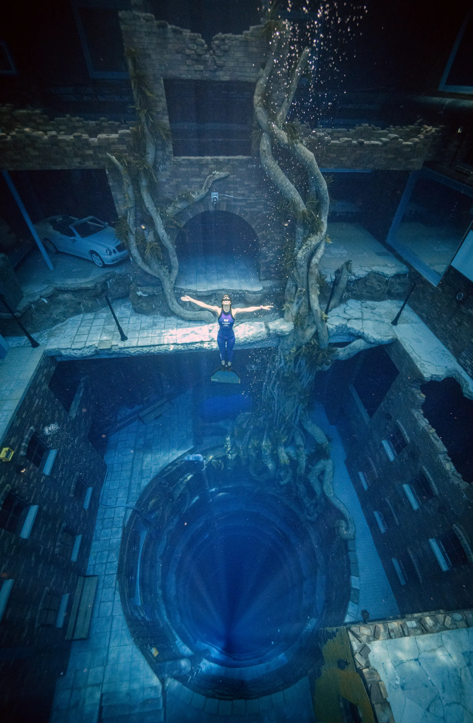woman scuba diving deep in the Dubai pool filled with fish and architecture