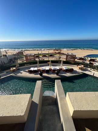 View of Waldorf Astoria Los Cabos Pedregal overlooking the spa pool, resort pool, and ocean and beach below from the lobby