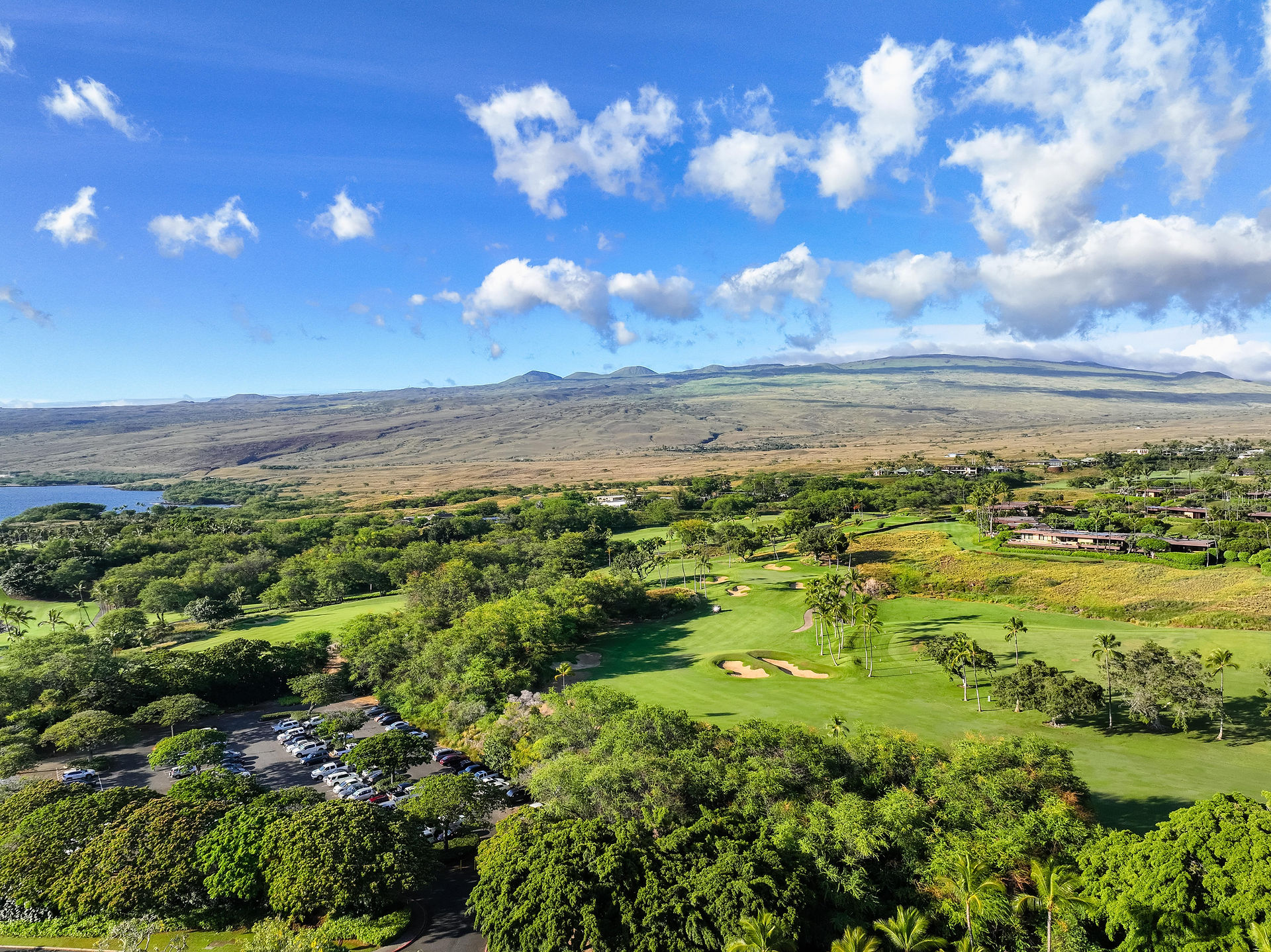 lush green golf course surrounded by the Mauna Kea volcano in the distance 
