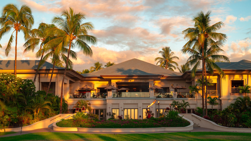 golden hour lighting illuminated on the main lobby and open air atrium of the fairmont orchid surrounded by lush landscaping and palm trees
