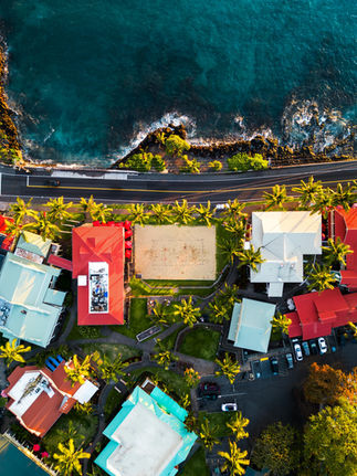 arrival view looking down at the main road in Kona as restaurants and crashing waves line both side